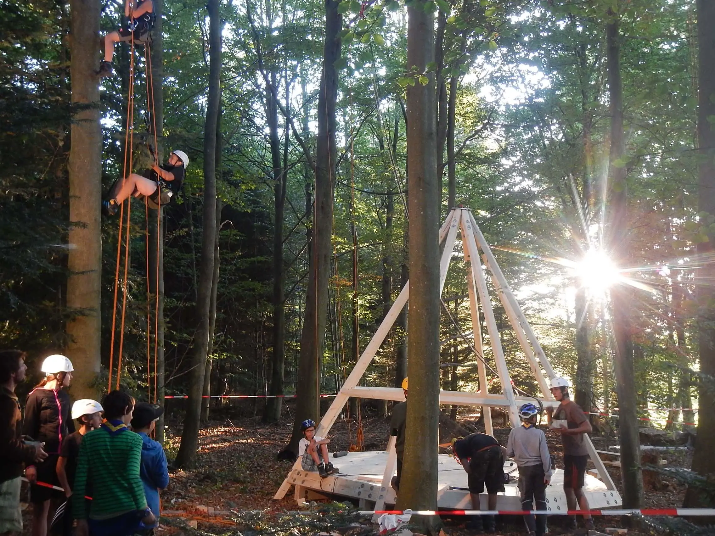 Baumhausbau unter der Pädagogischen Leitung von Tobias Weissenmayer. Man sieht Kinder und Jugendliche beim bedienen von Werkzeug, beim Klettern und beim Baumhausbau. Alle haben sehr viel spaß. in Bad Herrenalb.